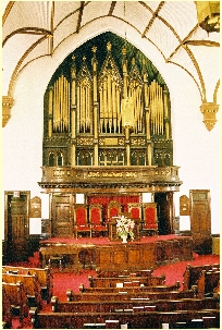 A picture of the interior of the Manhattan Seventh-Day Adventist church, with red carpet and an impressive pipe organ.